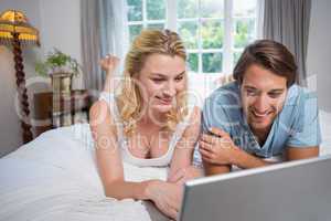 Cute couple relaxing on bed using the laptop