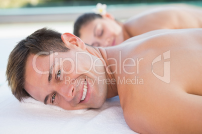 Attractive couple enjoying hot stone massage poolside