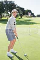 Lady golfer on the putting green at the eighteenth hole smiling