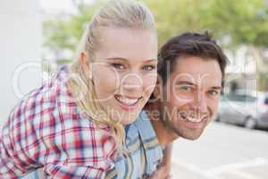 Young hip man giving his blonde girlfriend a piggy back