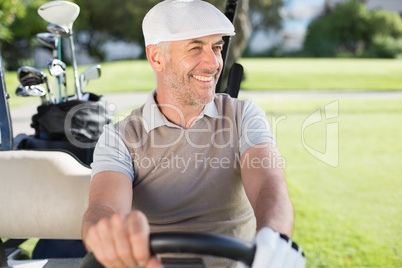 Happy golfer driving his golf buggy