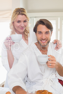 Cute couple in bathrobes having breakfast together