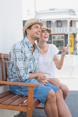 Young hip couple sitting on bench smiling