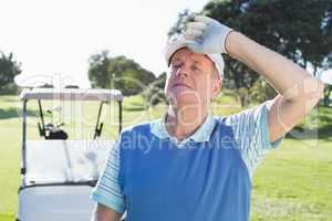 Happy golfer looking at camera with golf buggy behind