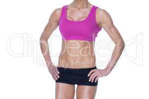 Female bodybuilder posing in pink sports bra and shorts mid sect