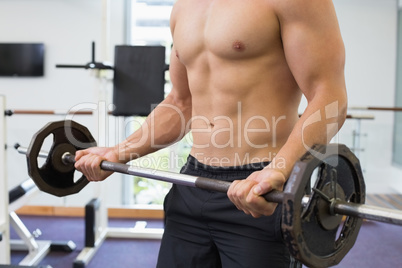 Shirtless bodybuilder lifting heavy barbell weight