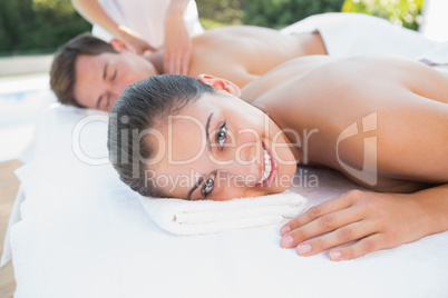 Attractive couple enjoying couples massage poolside