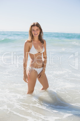 Beautiful smiling woman in white bikini standing in the sea