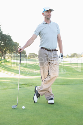 Handsome golfer standing with club