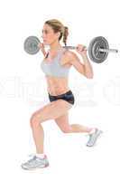 Serious female crossfitter lifting barbell behind head