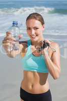 Fit woman standing on the beach holding water bottle and skippin