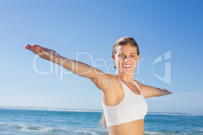 Sporty blonde standing on the beach with arms out