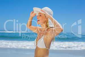 Smiling blonde in white bikini and sunhat on the beach