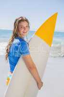 Fit happy surfer girl on the beach with her surfboard