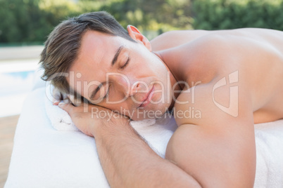 Peaceful man lying on massage table poolside