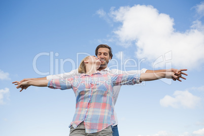 Happy couple standing outside with arms stretched kissing