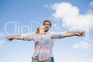 Happy couple standing outside with arms stretched kissing