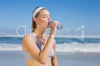 Sporty blonde drinking water on the beach