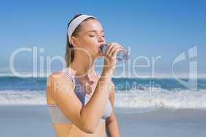 Sporty blonde drinking water on the beach