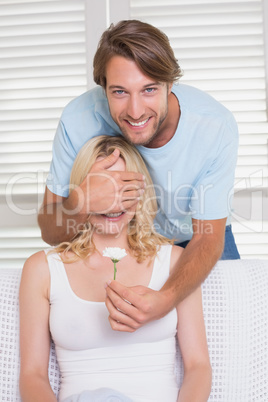 Man surprising his girlfriend with a flower on the couch