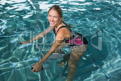 Fit happy blonde using underwater exercise bike