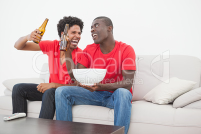 Football fans sitting on couch drinking beer