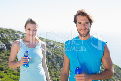 Fit couple standing at summit smiling at camera