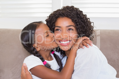 Pretty mother sitting on the couch with her daughter kissing her