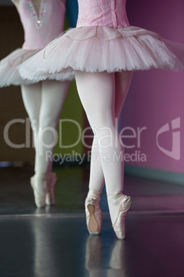 Graceful ballerina standing en pointe in front of mirror