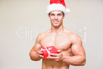 Shirtless macho man in santa hat holding gift