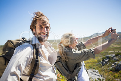 Hiking couple standing on mountain terrain taking a selfie