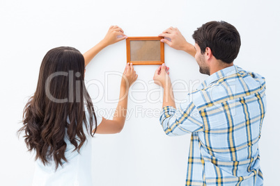 Happy young couple putting up picture frame