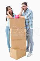 Happy young couple with moving boxes and piggy bank
