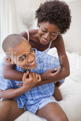 Happy couple messing about in bed together