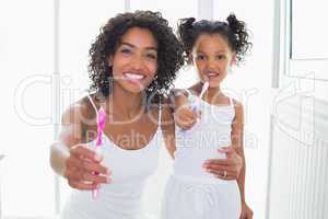 Pretty mother and daughter showing toothbrushes