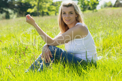 Pretty blonde smiling at camera sitting on grass