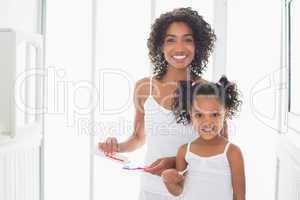 Pretty mother with her daughter brushing their teeth