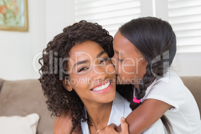 Pretty mother sitting on the couch with her daughter smiling at