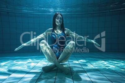 Athletic swimmer smiling at camera underwater