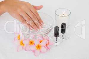 Hand in bowl along flowers and candle