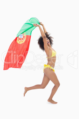 Athletic girl in yellow bikini holding portugal flag