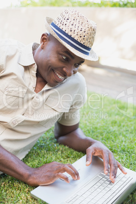 Smiling man relaxing in his garden using laptop