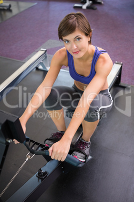 Fit smiling brunette working out on rowing machine