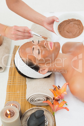 Peaceful brunette getting a mud treatment facial