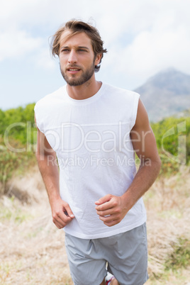 Attractive man jogging on mountain trail