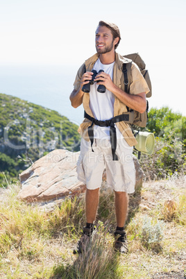 Handsome hiker holding binoculars on mountain trail