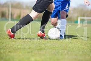 Football players tackling for the ball on pitch