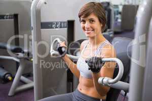 Healthy happy brunette using weights machine for arms