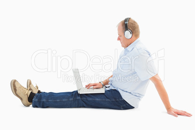 Mature man using laptop listening to music