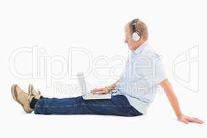 Mature man using laptop listening to music